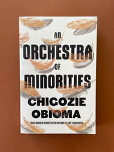 Load image into Gallery viewer, An Orchestra of Minorities by Chigozie Obioma: photo of the front cover which shows very minor (barely visible) scuff marks along the edges.