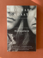 Load image into Gallery viewer, Divisadero by Michael Ondaatje: photo of the front cover which shows very minor scuff marks along the edges.