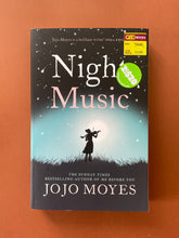 Load image into Gallery viewer, Night Music by Jojo Moyes: photo of the front cover which shows very minor (barely visible) scuff marks along the edges, and minor creasing running down the left side, parallel to the spine.