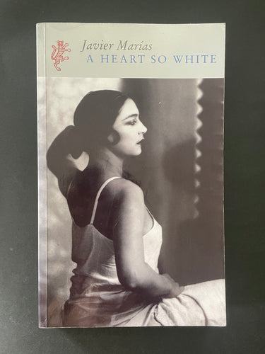 Book cover of 'A Heart So White' by Javier Marías with a black and white photo of a woman on the cover. There is a fair amount of faint creasing on the cover that the camera has not picked up, and some minor creasing along the edges.