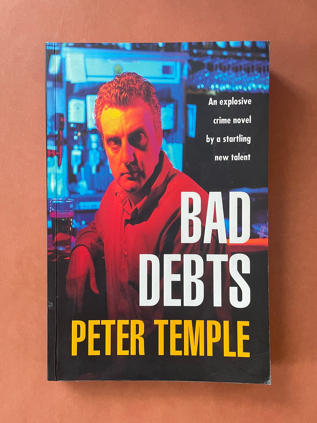 Bad Debts by Peter Temple: photo of the front cover which shows very minor scratching, and obvious creasing on the bottom-left corner.