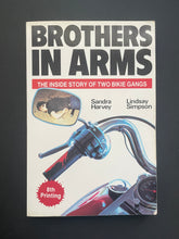 Load image into Gallery viewer, Book cover of &#39;Brothers in Arms&#39; by Sandra Harvey &amp; Lindsay Simpson with motorcycle image on a dark background. There are some minor scuff marks along the edges, and some creasing on the bottom-right corner. 
