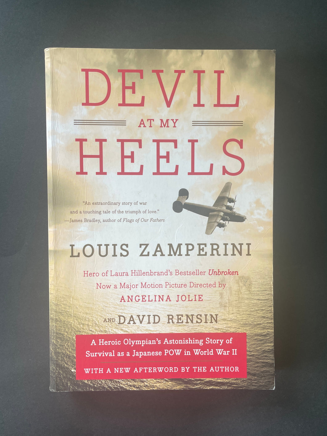 Devil at My Heels by Louis Zamperini: photo of the front cover which shows very fine creases running down the left-hand side, and very fine creasing on the top-right corner, none of which is overly noticeable.