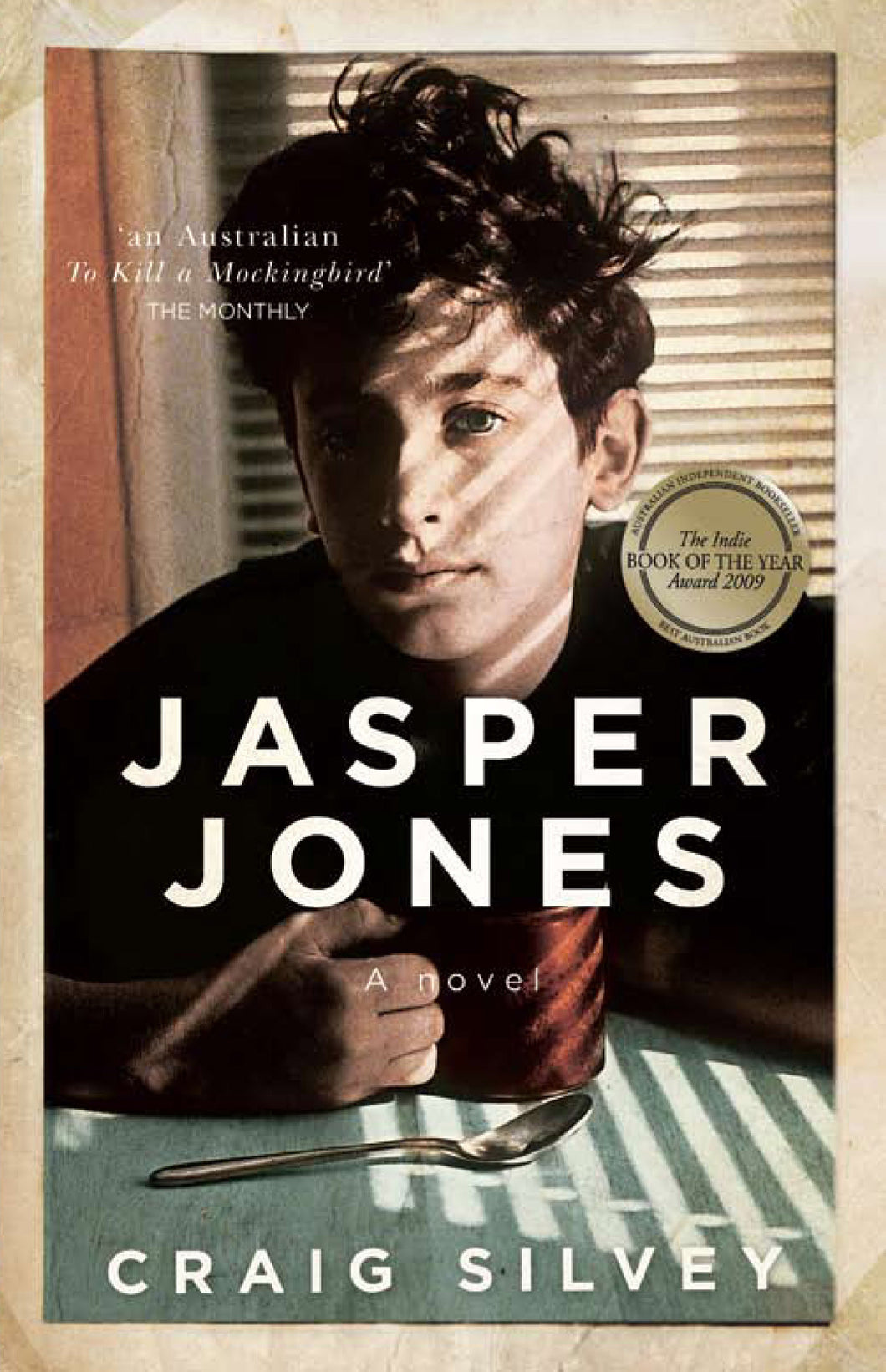 Book cover for 'Jasper Jones' by Craig Silvey which features a picture of a boy sat at a table with a mug in his hand and a spoon on the table.