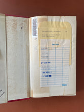 Load image into Gallery viewer, One Day in the Life of Ivan Denisovich: photo of the inside of the front covwer, which has yellowed with age, and the first page, which has old cardboard library card pockets stuck on it along with a library barcode sticker. This first page has also discoloured somewhat with age.
