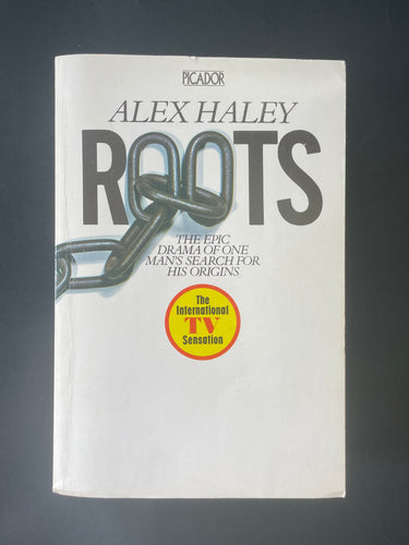 Roots by Alex Haley: photo of the front cover which shows very minor scuff marks along the edges, and minor creasing running down the left-hand side of the book, parallel to the spine.