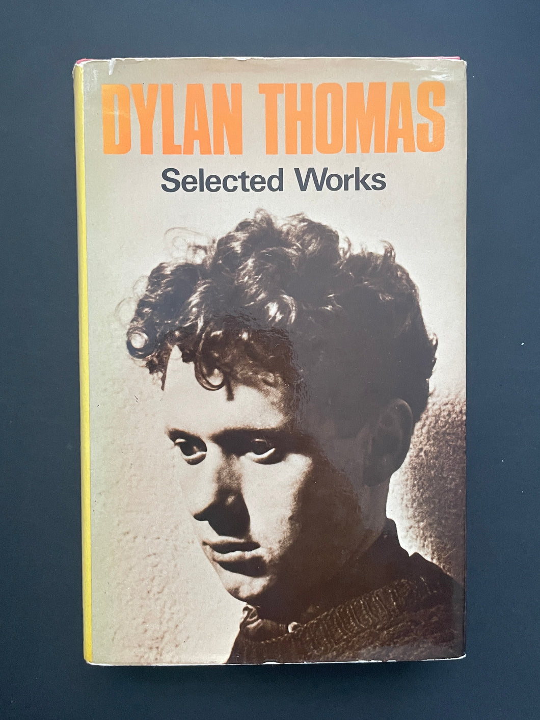 Book cover of 'Selected Works' by Dylan Thomas with a portrait on a dark background. There photo shows scuff markd along the edges, and a tiny tear on the top-left side of the dust jacket.