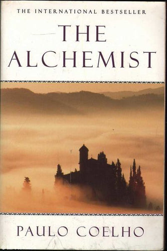 Book cover of 'The Alchemist' by Paulo Coelho with a castle silhouette in the mist.