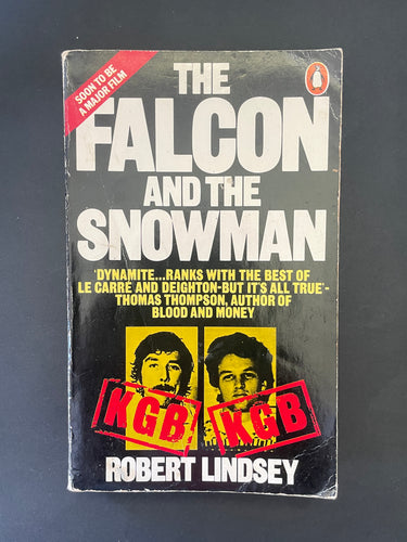 Book cover of 'The Falcon and the Snowman' by Robert Lindsey on a dark background. The photo shows obvious creasing and scuff marks.