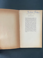 Load image into Gallery viewer, The Plague by Albert Camus: photo of the inside of the front cover and the first page. The inside of the front cover has browned considerably with age.
