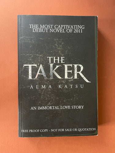 The Taker by Alma Katsu: photo of the front cover which shows very minor scuff marks along the edges and very minor scratching.