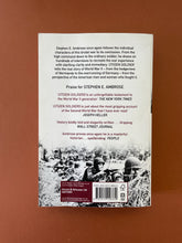 Load image into Gallery viewer, Citizen Soldiers by Stephen E. Ambrose: photo of the back cover which shows very minor scuff marks along the edges. You can also see a very slight vertical bend down the length of the cover.
