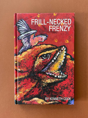 Frill-Necked Frenzy by Kenneth Cook: photo of the front cover which shows a faint line imprinted on the top-left corner, and very minor scuff marks along the edges.