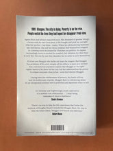 Load image into Gallery viewer, Shuggie Bain by Douglas Stuart: photo of the back cover which shows minor scuff marks and creasing along the edges.
