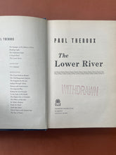 Load image into Gallery viewer, The Lower River by Paul Theroux: photo of the title page which shows that the page has been stamped with the word: WITHDRAWN in red stamp.
