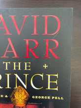 Load image into Gallery viewer, The Prince by David Marr book: photo of very minor scuff mark on the top-right corner of the front cover. Also visible is a small scratch between the red letters D and R.
