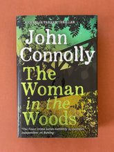 Load image into Gallery viewer, The Woman in the Woods by John Connolly: photo of the front cover which shows very minor (barely visible) scuff marks along the edges of the dust jacket.
